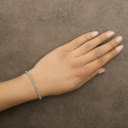 Yellow bracelet with white round gemstones in prong settings, shown worn on a model's wrist, angled top-down on a textured surface.