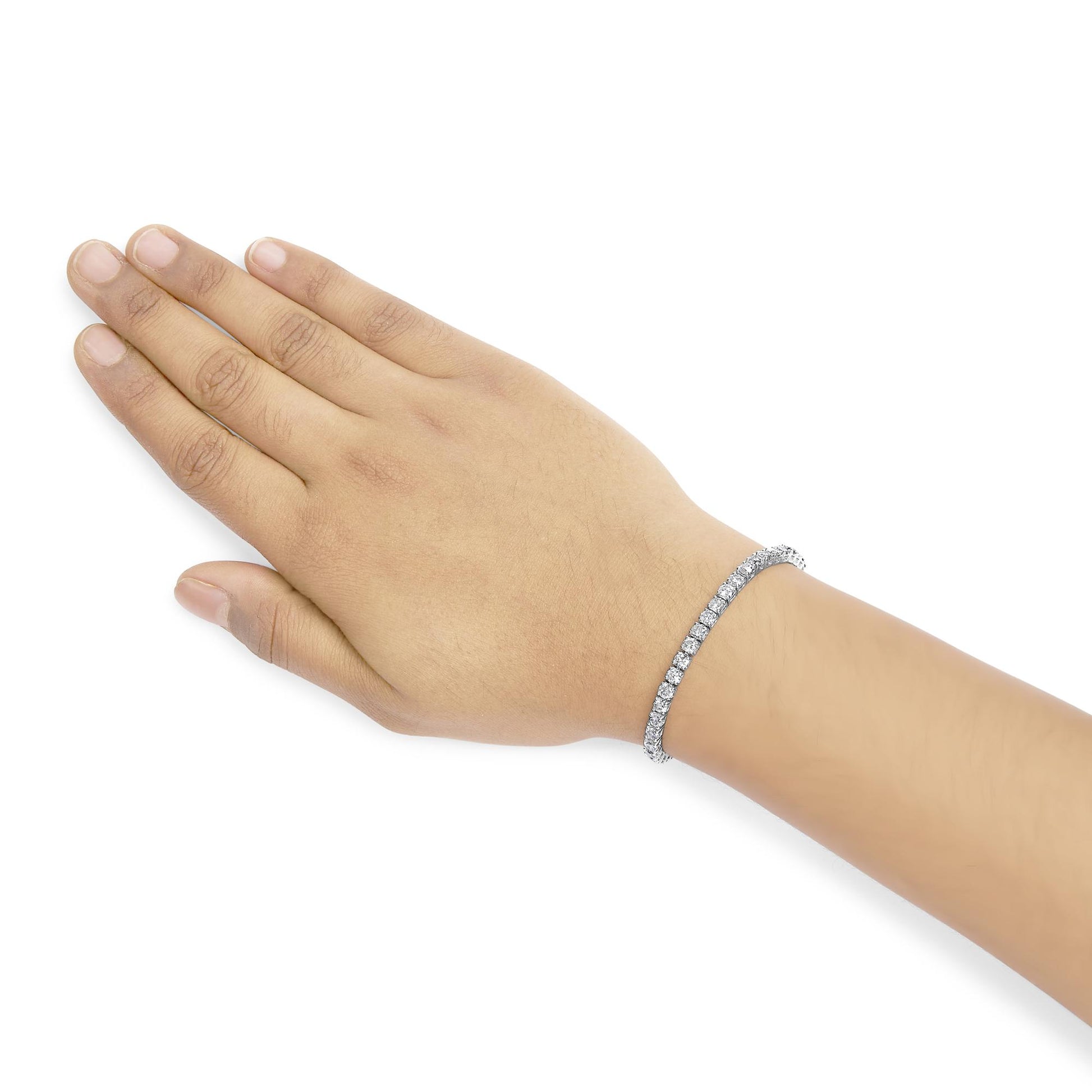 White metal bracelet with round white gemstones in four-prong settings, worn on a model's wrist, angled top-down view.