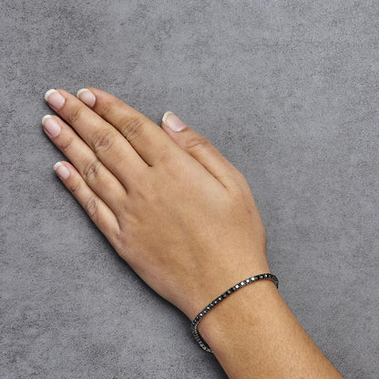 White metal bracelet with black round gemstones in prong setting, worn on a model’s wrist, top-down view.