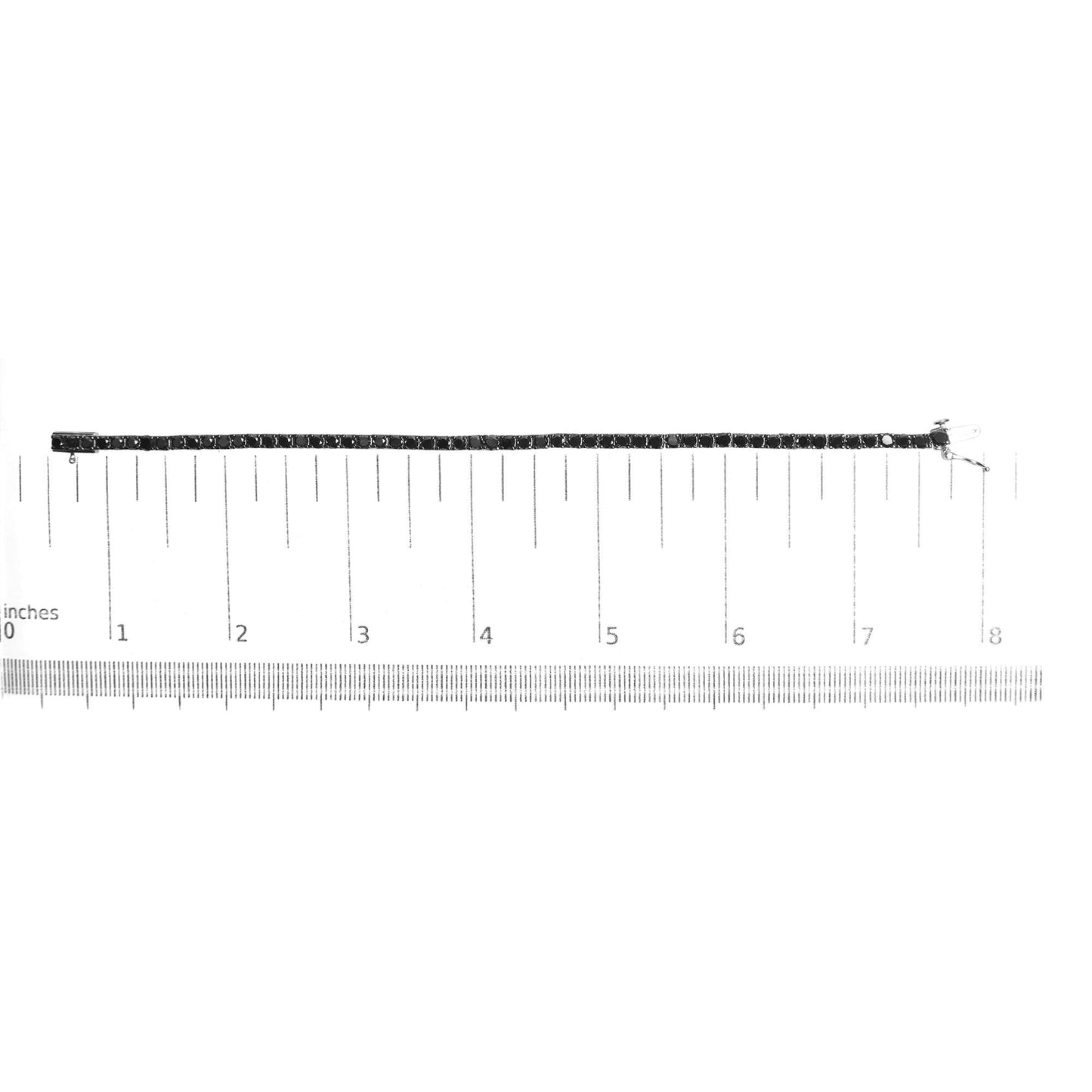 White metal bracelet with round black gemstones in prong settings, laid flat on a ruler for size reference, top-down angle.