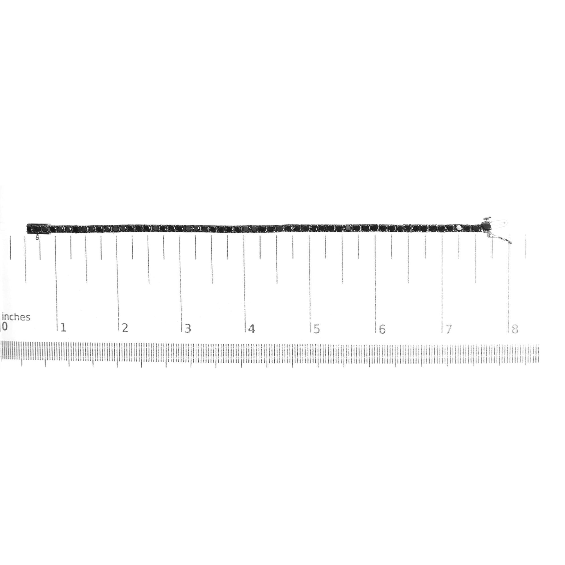 White metal bracelet with round black gemstones in prong settings, laid flat on a ruler for size reference, top-down angle.