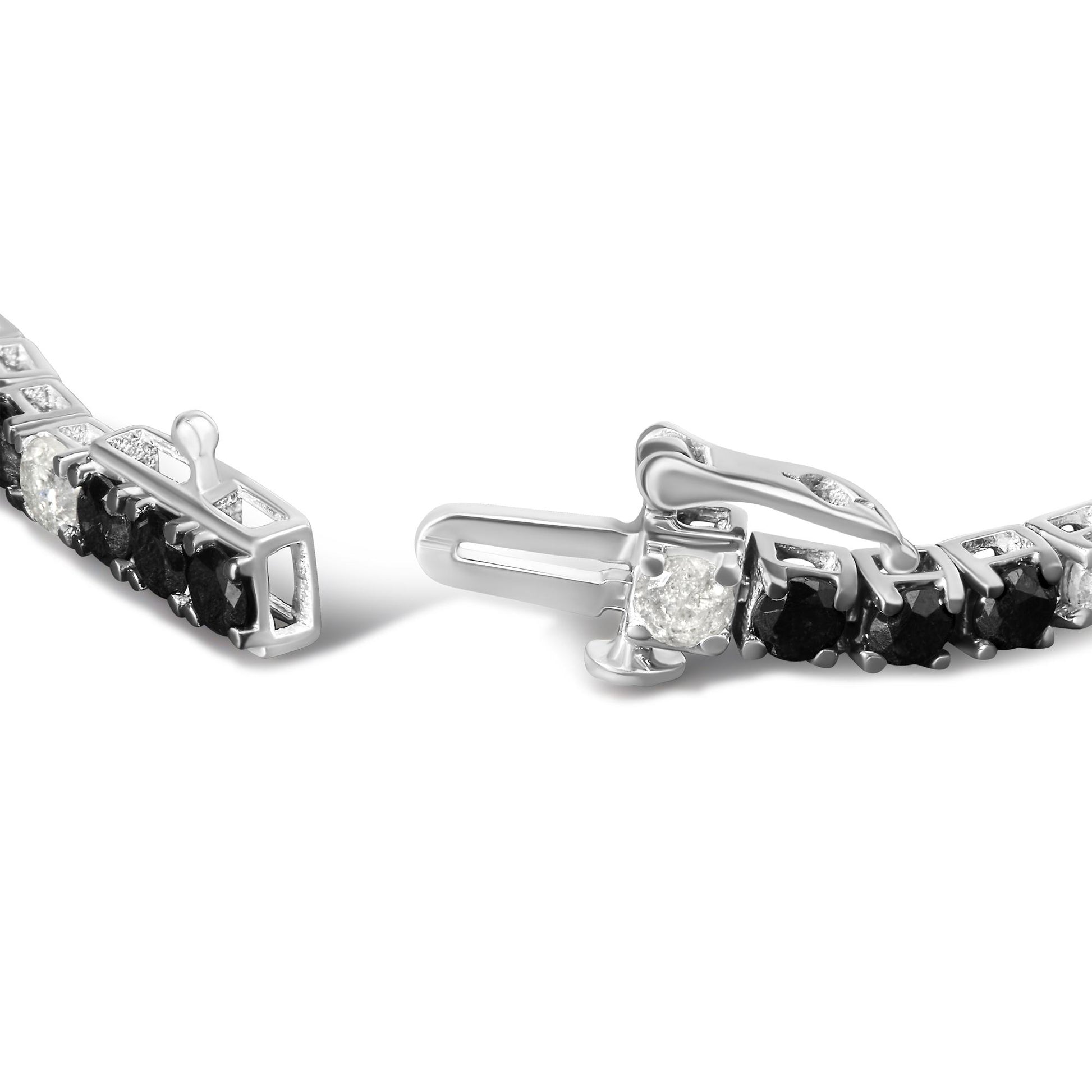 Close-up angled view of a white metal bracelet with alternating round black and white gemstones in 4-prong settings, showing the clasp open.