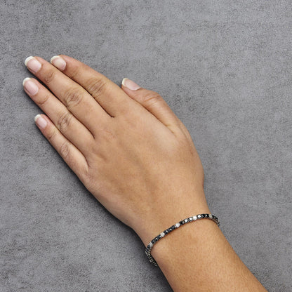 Close-up angled view of a white metal bracelet with alternating black and white round gemstones in 4-prong settings, worn on a model's wrist.