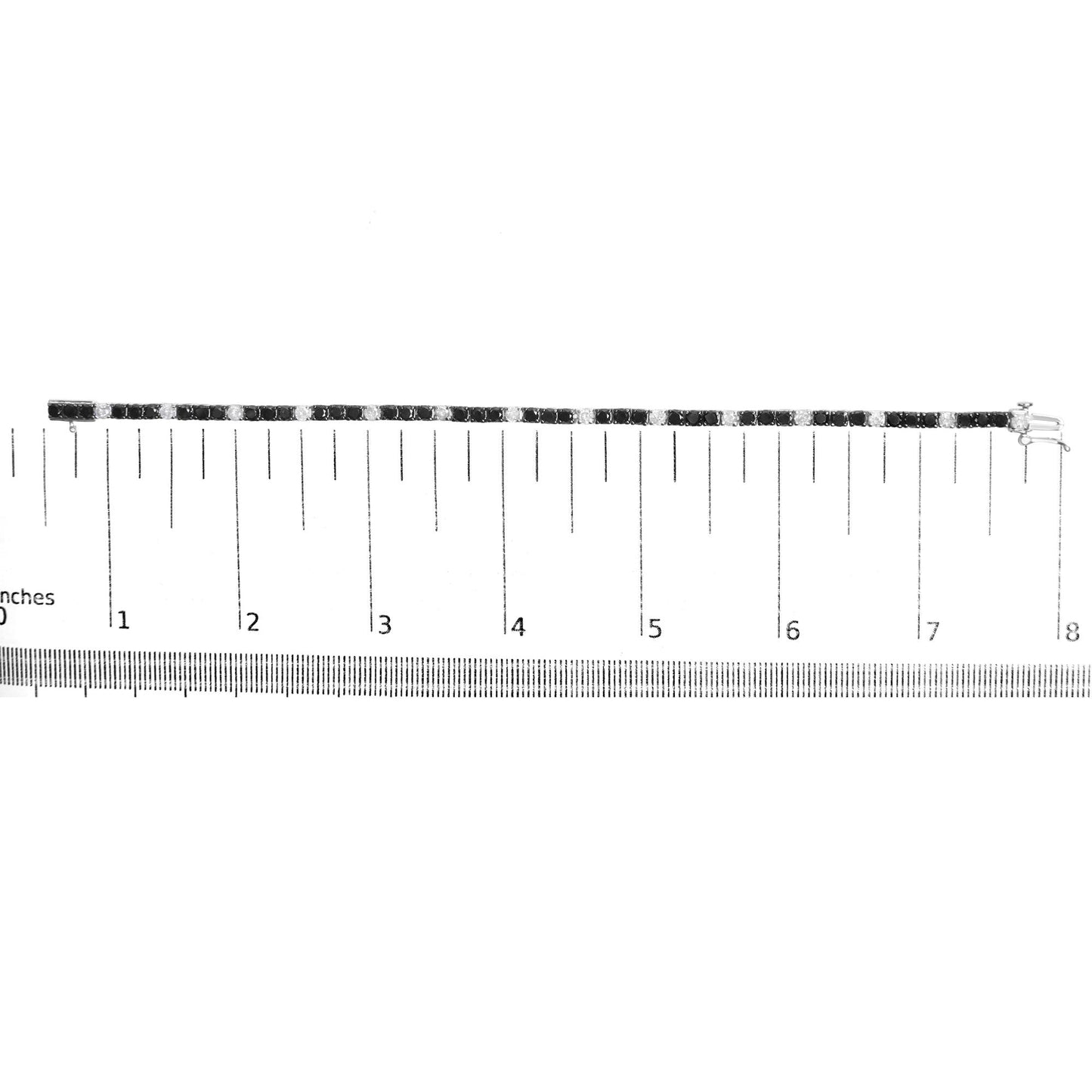 White metal bracelet with alternating black and white round gemstones in 4-prong settings, laid flat on a ruler for size reference, side view.