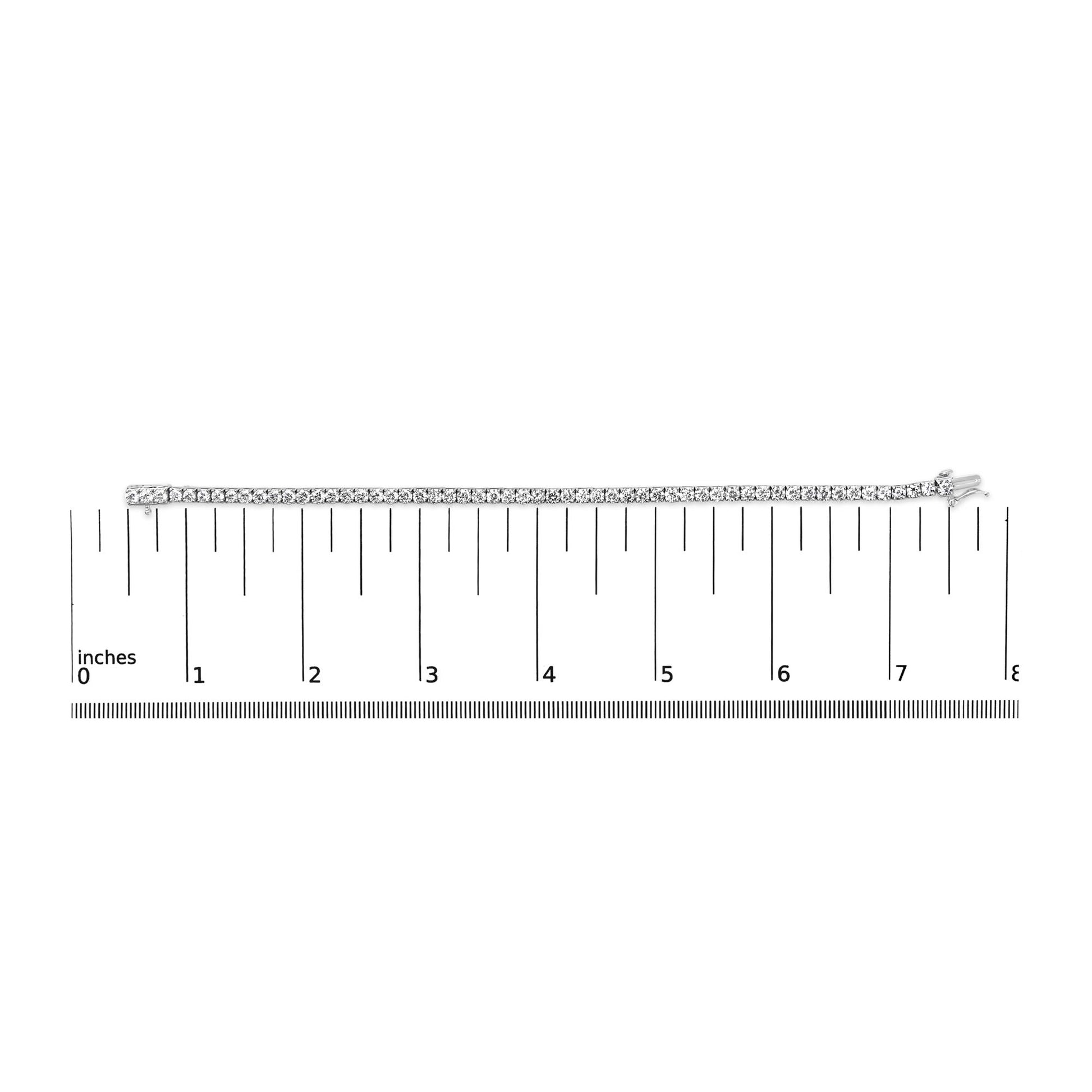 White metal bracelet with round white gemstones in 4-prong settings, laid flat on a ruler for size reference, top-down angle.