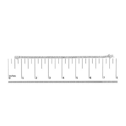 White metal bracelet with round white gemstones in 4-prong settings, laid flat on a ruler for size reference, top-down angle.