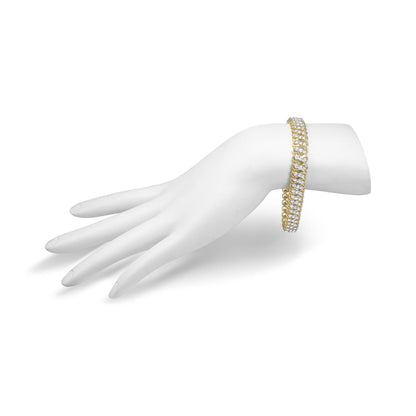 Yellow metal bracelet with white round gemstones in shared prong setting shown on a white display hand from a side angle.