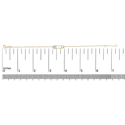 Yellow metal bracelet with a safety pin charm adorned with white round gemstones in prong settings, shown on a measuring scale from above.