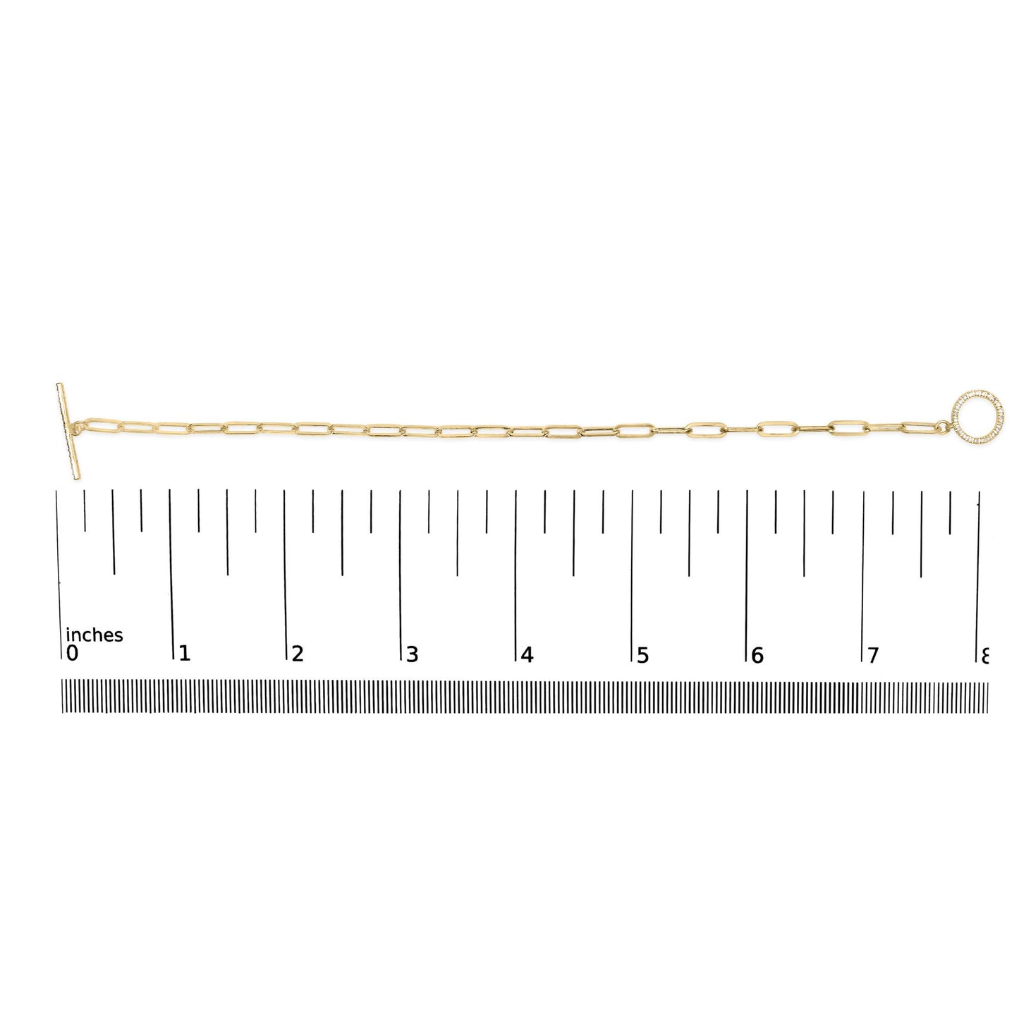 Top-down view of a yellow metal bracelet with elongated links, featuring a circular charm set with white round gemstones, displayed on a ruler for size reference.