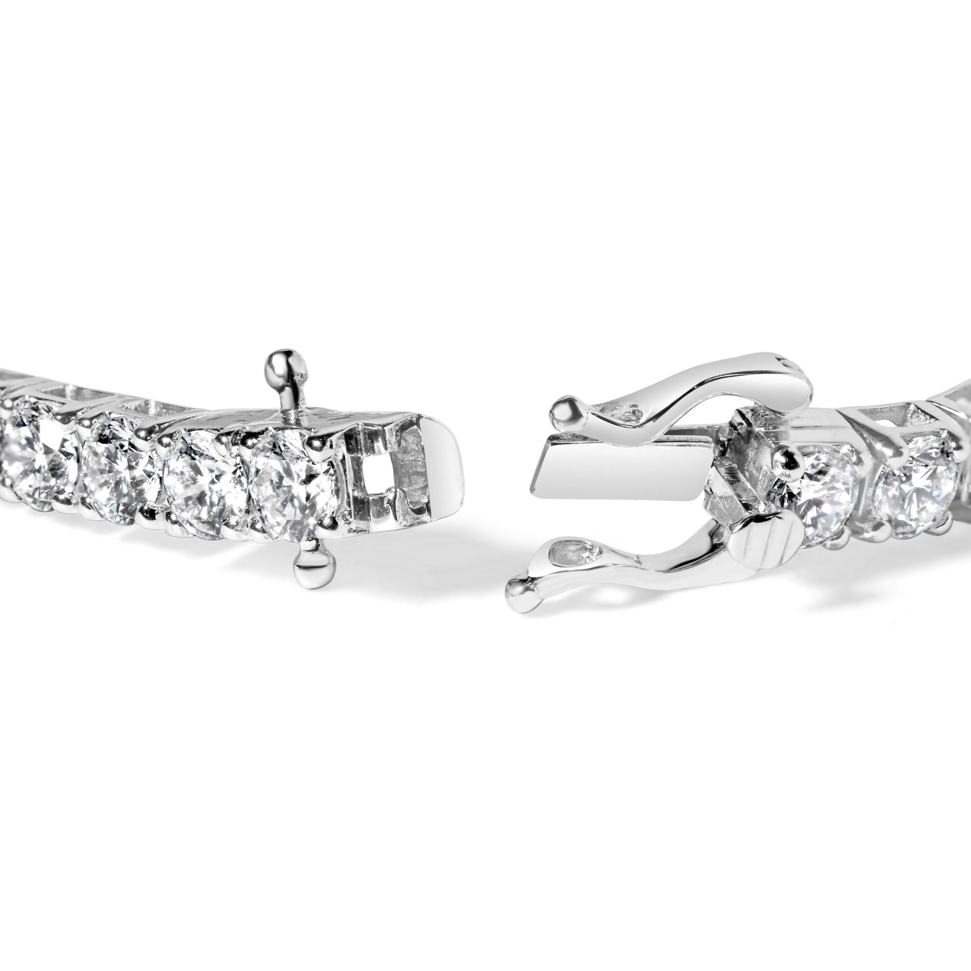 Close-up front angle of a white metal bracelet featuring round white gemstones in 4-prong settings with an open clasp.