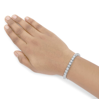 White metal bracelet with round white gemstones in 4-prong settings on a model's wrist, shot from above.