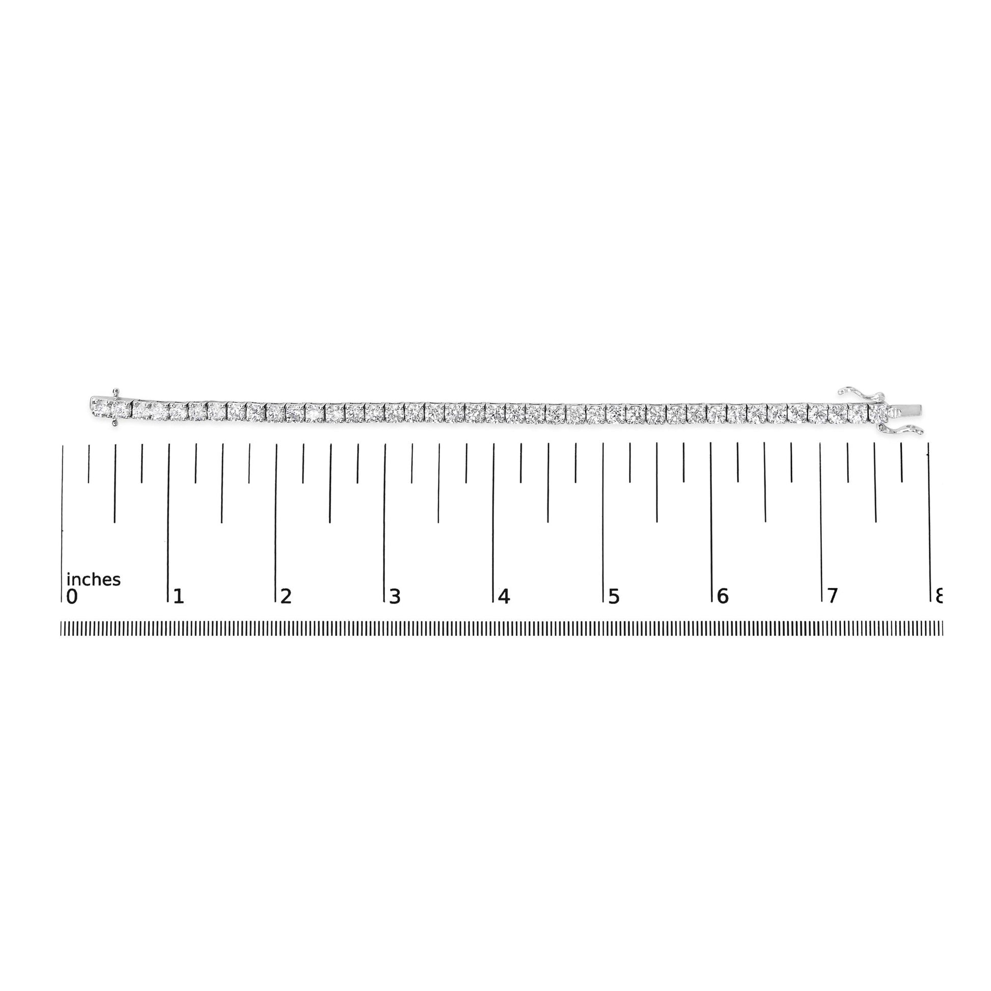 White metal bracelet with round white gemstones in 4-prong settings, laid flat on a ruler for size reference, top-down angle.