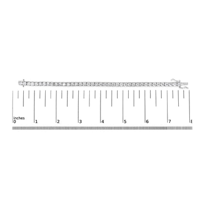 White metal bracelet with round white gemstones in 4-prong settings, laid flat on a ruler for size reference, top-down angle.