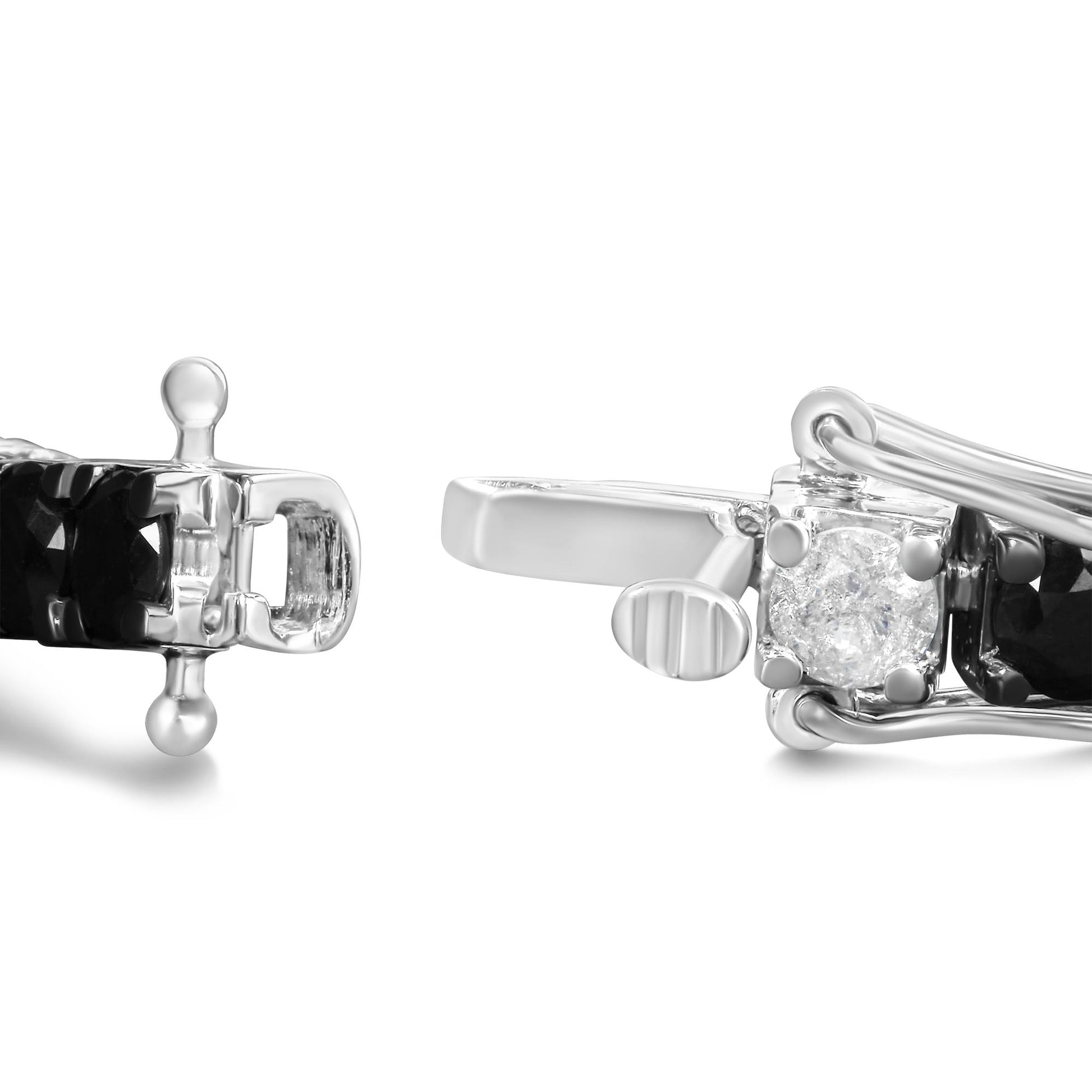 Close-up side angle of white metal bracelet clasp featuring round white and black gemstones in 4-prong settings.
