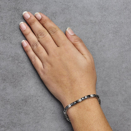 White metal bracelet with alternating black and white round gemstones in 4-prong settings, shown on a model's wrist from top-down angle.