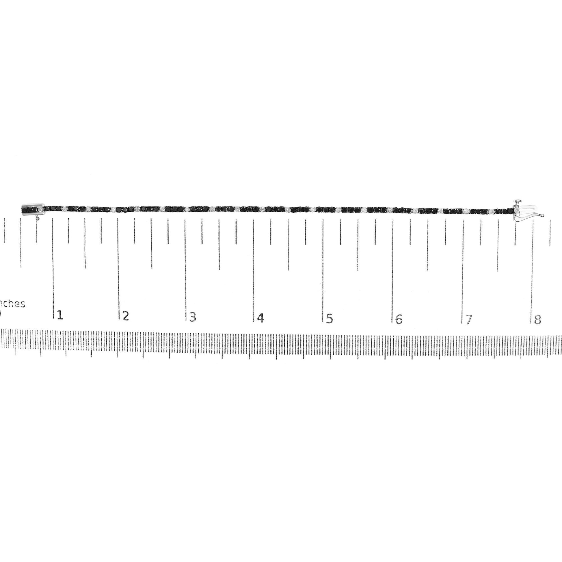 White metal bracelet with alternating round black and white gemstones in 4-prong settings, displayed flat on a ruler for size reference, top-down view.