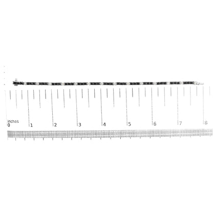 White metal bracelet set with alternating black and white round gemstones in 4-prong settings, laid flat on a ruler for size reference, shot from above.