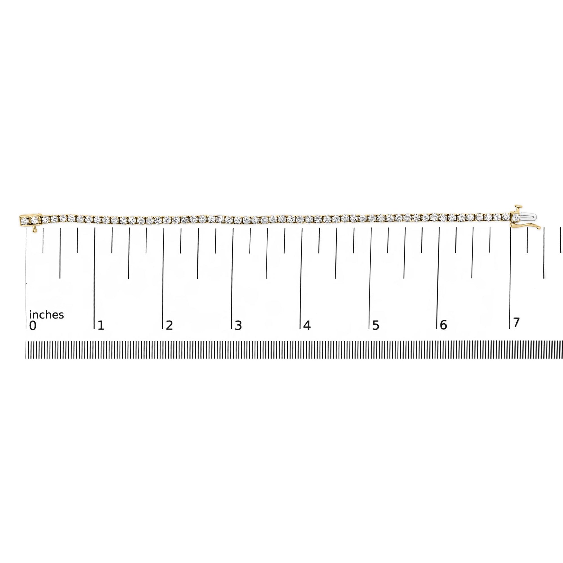 Yellow metal bracelet with round white gemstones in 4-prong settings, displayed flat on a ruler for size reference, photographed from above.