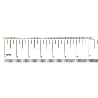 Yellow metal bracelet with round white gemstones in 4-prong settings, displayed flat on a ruler for size reference, photographed from above.