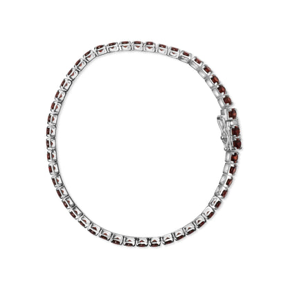 Top-down view of a white metal bracelet with round orange gemstones in 4-prong settings all around.