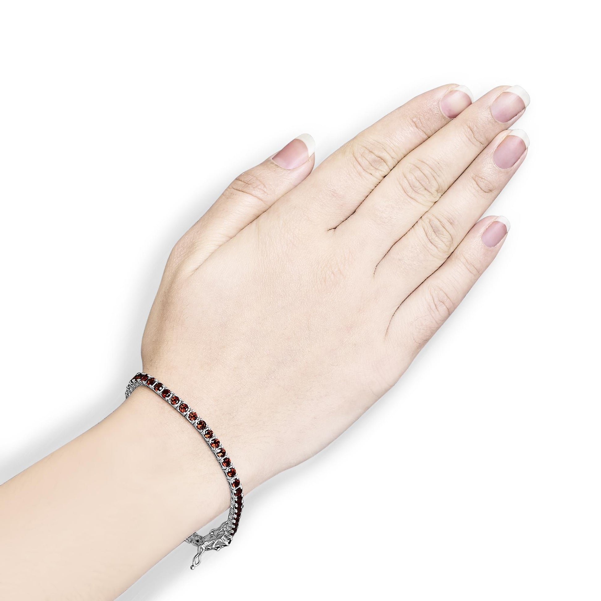 White metal bracelet with small round orange gemstones in 4-prong settings, shown on a model's wrist from a top-down angle.