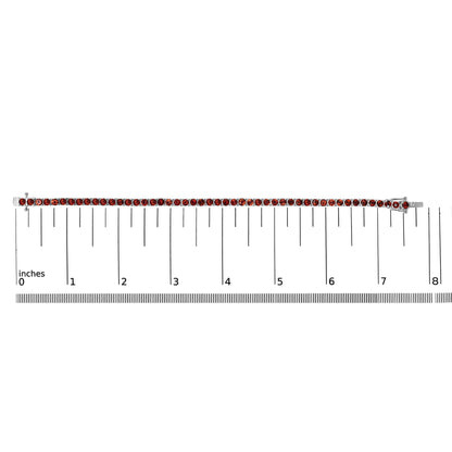 White metal bracelet with round orange gemstones in 4-prong settings, laid flat on a ruler for size reference, top-down angle.