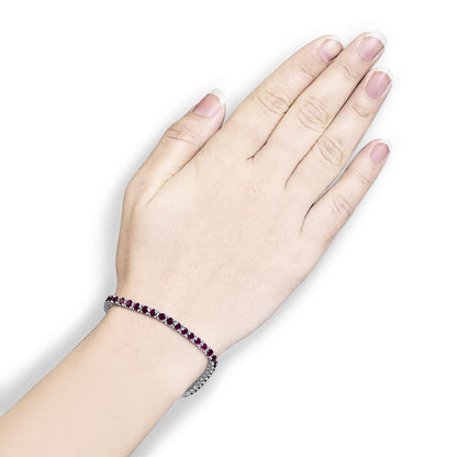 White metal bracelet with round pink gemstones in 4-prong settings, shown on a model's wrist, top-down angle.