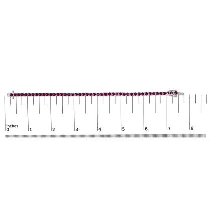 White metal bracelet with round pink gemstones in four-prong settings, displayed horizontally on a ruler for size reference, front-facing angle.