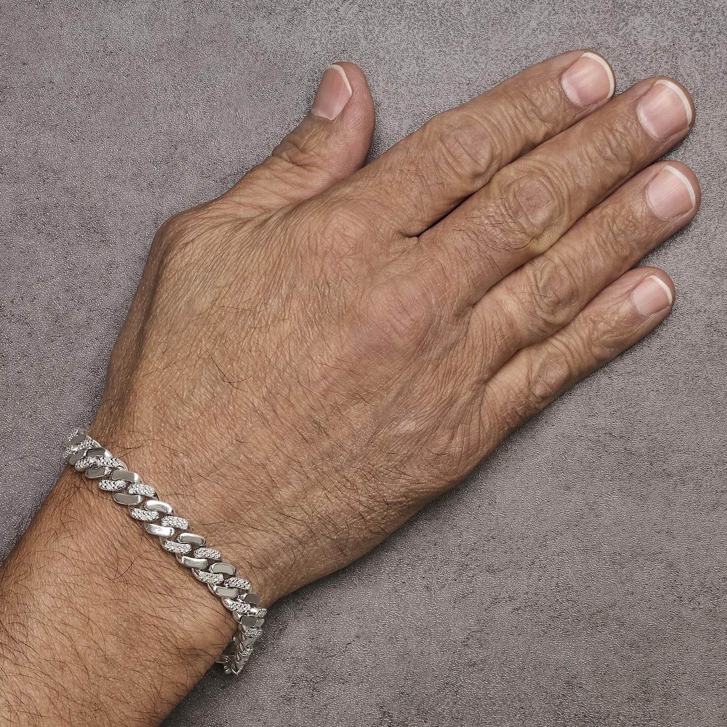 White metal bracelet with alternating polished and white gemstone-studded links, shown on a model's wrist, viewed from the top angle.