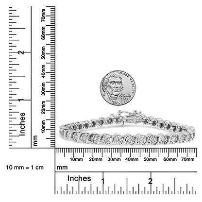 White bracelet with round white gemstones in a curved setting, shown from a side angle on a ruler and scale for size reference with a coin above it.