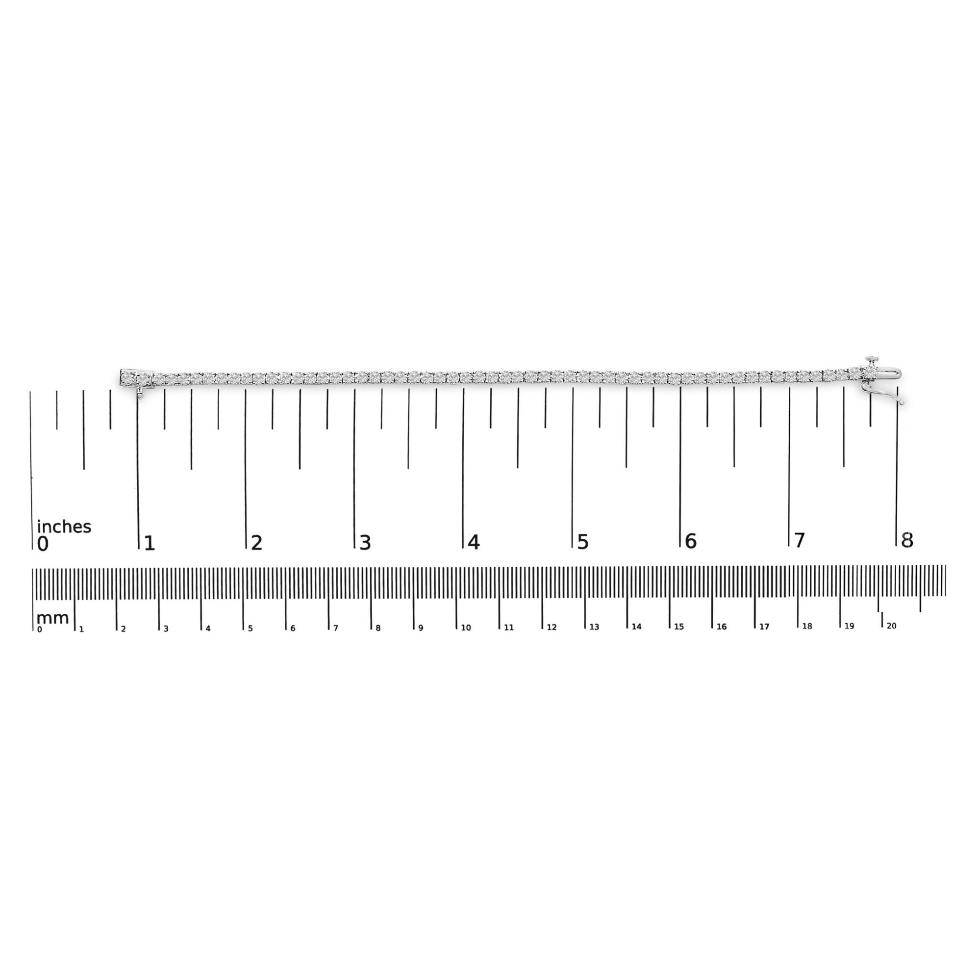 White metal bracelet with round white gemstones in four-prong settings, positioned flat on a ruler for size reference, top-down view.