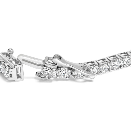 Close-up side angle of a white metal bracelet with round white gemstones in prong settings, featuring an open clasp.