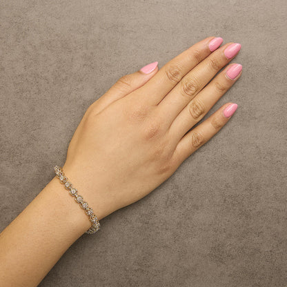 Yellow metal bracelet with round white gemstones in prong settings, shown worn on a model's wrist from a top angle.