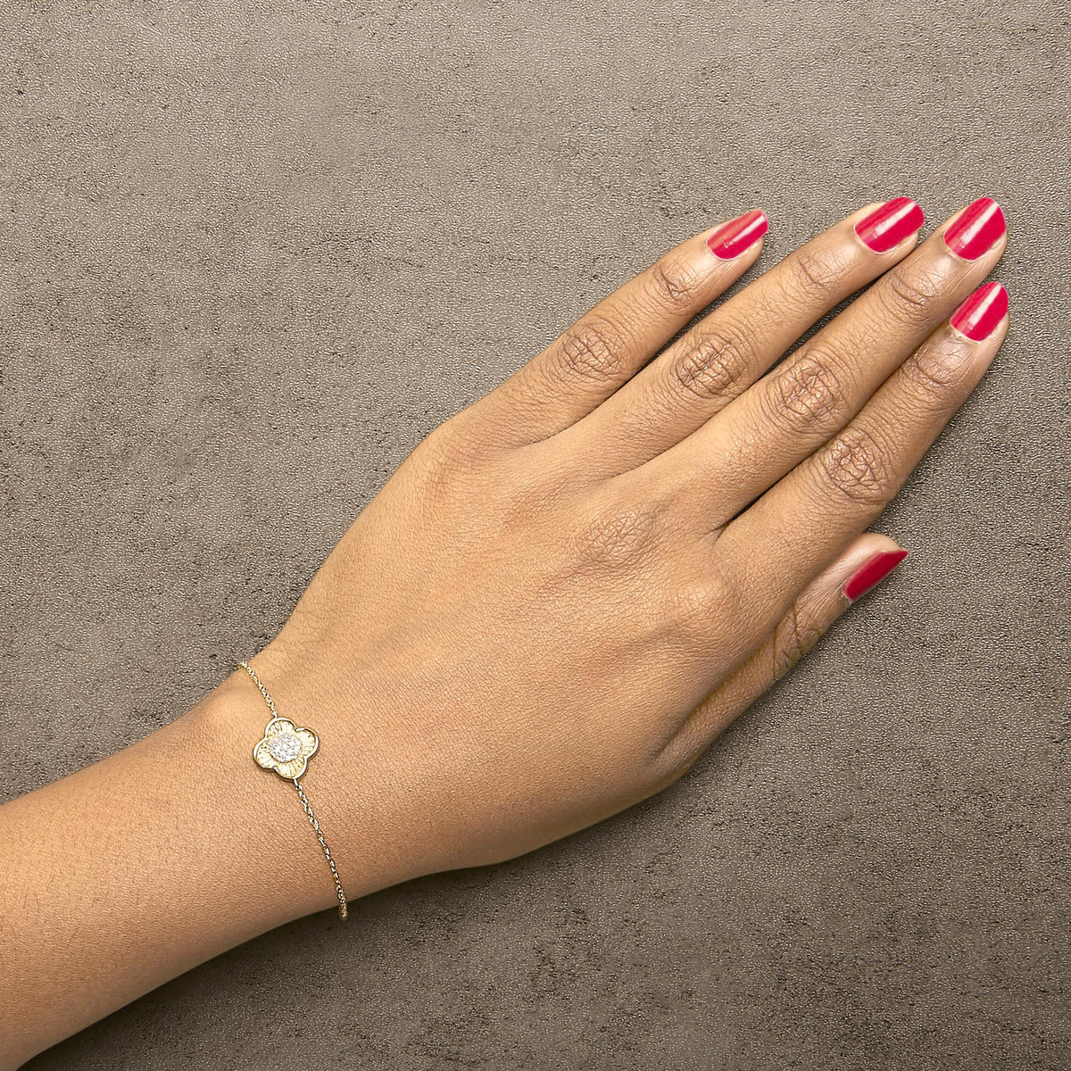 Yellow bracelet with a flower-shaped charm featuring round white gemstones in prong settings, shown worn on a model's wrist from a top angle.