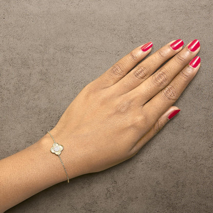 Yellow bracelet with a flower-shaped charm featuring round white gemstones in prong settings, shown worn on a model's wrist from a top angle.