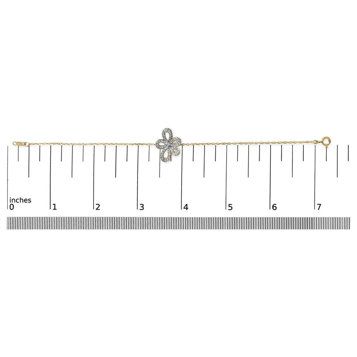 Yellow metal bracelet with a floral-shaped centerpiece set with white gemstones, shown flat on a measurement scale, top-down angle.