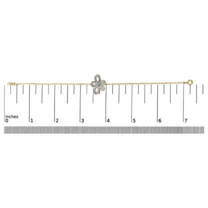 Yellow metal bracelet with a floral-shaped centerpiece set with white gemstones, shown flat on a measurement scale, top-down angle.