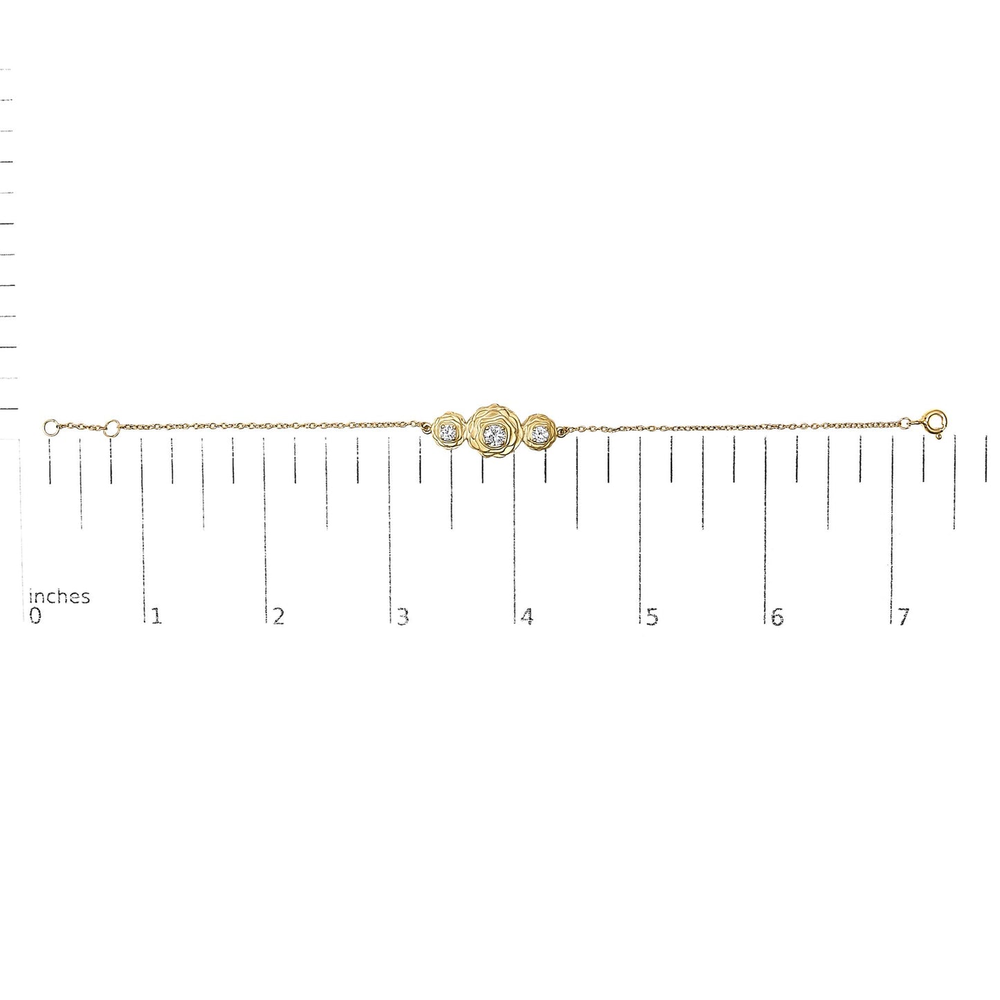 Yellow metal bracelet with three round white gemstones in prong settings arranged in a floral design, shown on a ruler scale from a top-down angle.