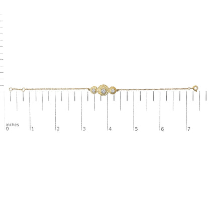 Yellow metal bracelet with three round white gemstones in prong settings arranged in a floral design, shown on a ruler scale from a top-down angle.
