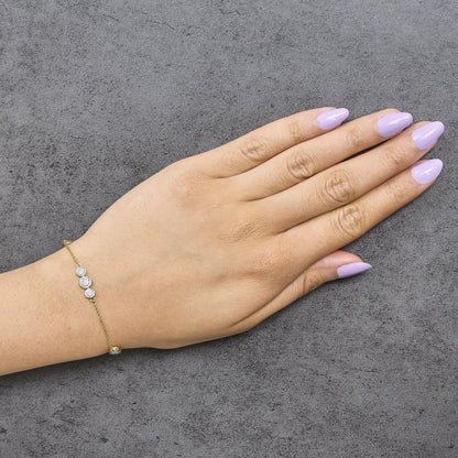 Yellow bracelet with white round gemstones in prong settings, shown worn on a model's wrist, top-down angle.