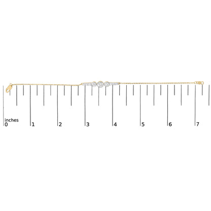Yellow metal bracelet with a central cluster of round white gemstones in prong settings, shown flat on a scale with a straight-on angle.