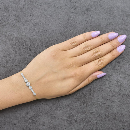 Yellow bracelet with multiple round white gemstones in prong and bezel settings, shown worn on a model's wrist from a top angle.