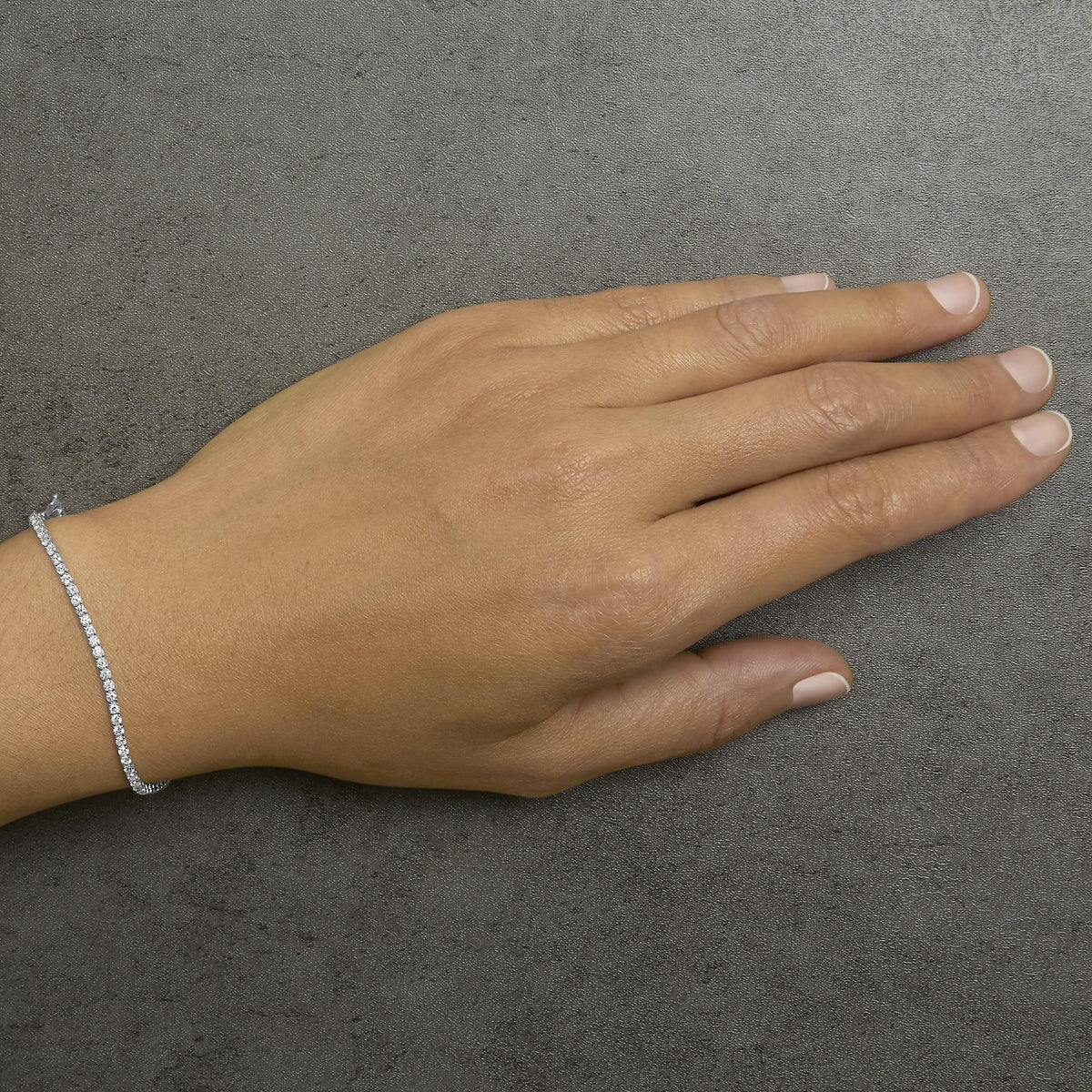 White round gemstone bracelet with prong setting shown on a model’s wrist, image taken from a top angle.