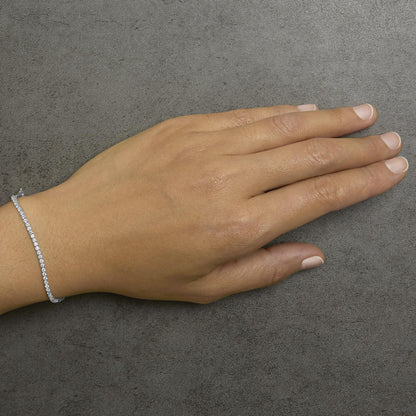 White round gemstone bracelet with prong setting shown on a model’s wrist, image taken from a top angle.