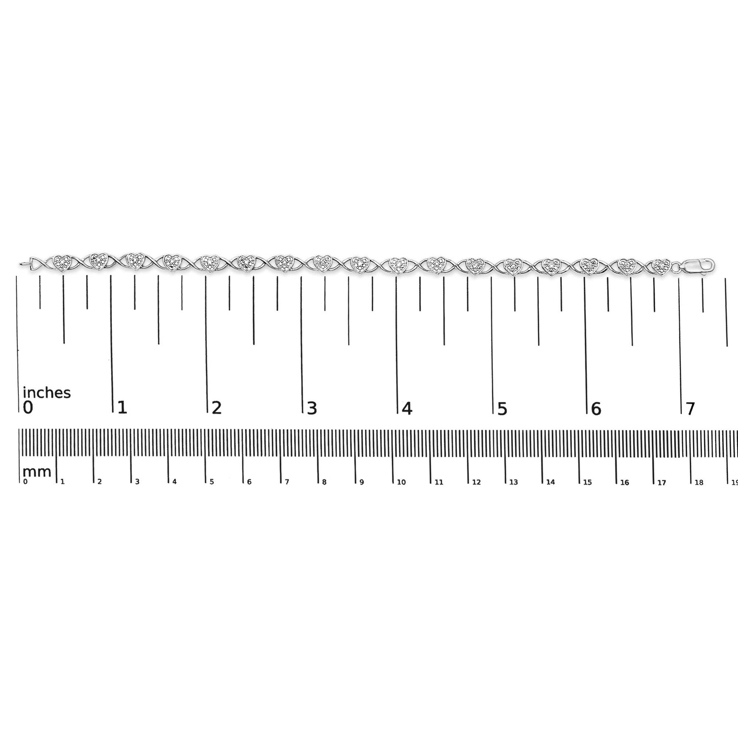 White metal bracelet with heart-shaped links each set with multiple small white gemstones, shown flat on a ruler for size reference, top-down view.
