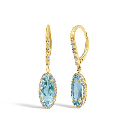 Close-up front view of yellow metal earrings featuring oval blue gemstones surrounded by a border of small white gemstones and accented with a line of small white gemstones along the upper part.