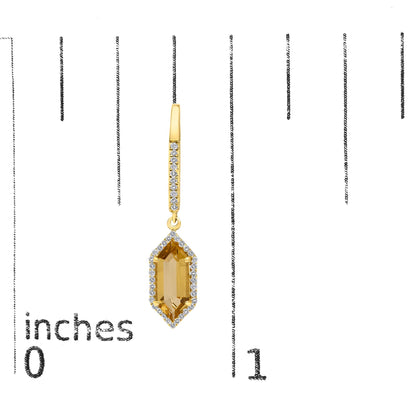 Close-up image of a yellow metal earring with round white gemstones in a micro-pave setting along the drop and a large yellow gemstone in a prong setting at the bottom, shown on a scale.
