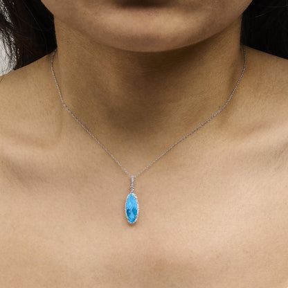 White metal necklace with a blue oval gemstone pendant surrounded by small white round gemstones in a micro-pave setting, shown worn on a model, front angle.