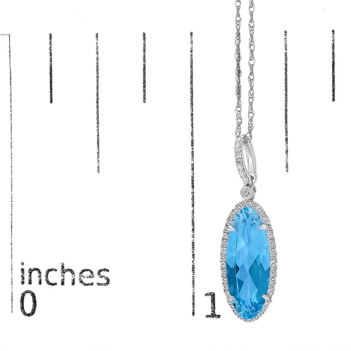 Close-up front view of a white metal necklace with an oval blue gemstone center surrounded by small round white gemstones in micro-pave setting, shown on a measurement scale.