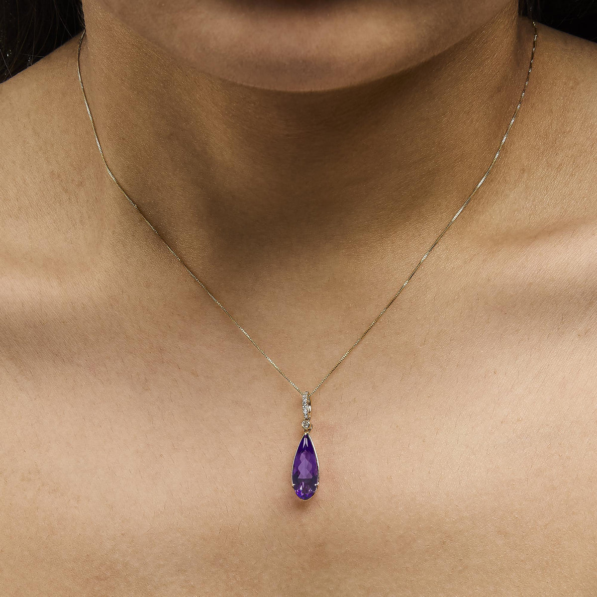 Front view of 10K yellow gold pear-shaped purple amethyst and diamond accent drop pendant necklace shown on a model